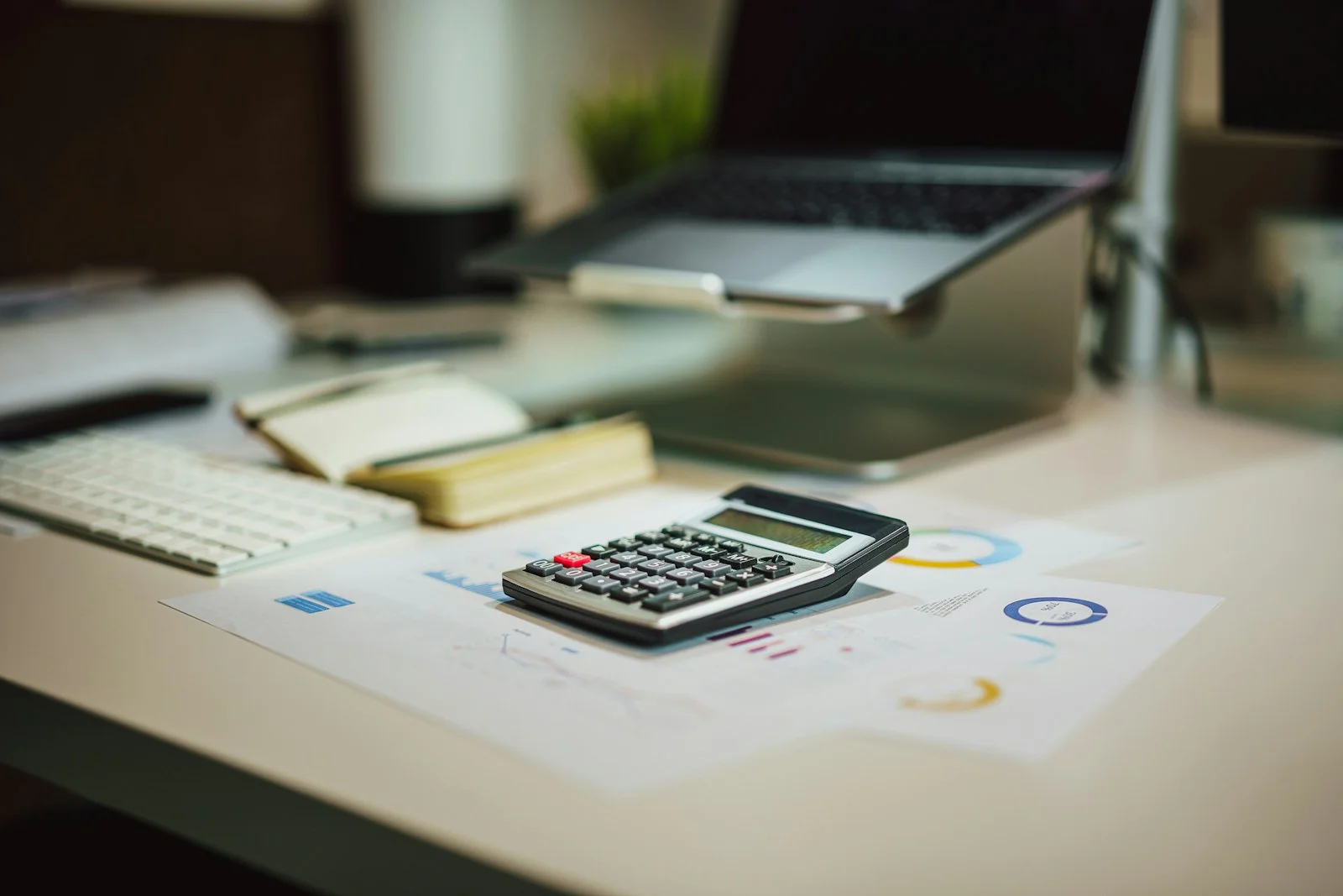 Desk with a calculator, charts and a laptop