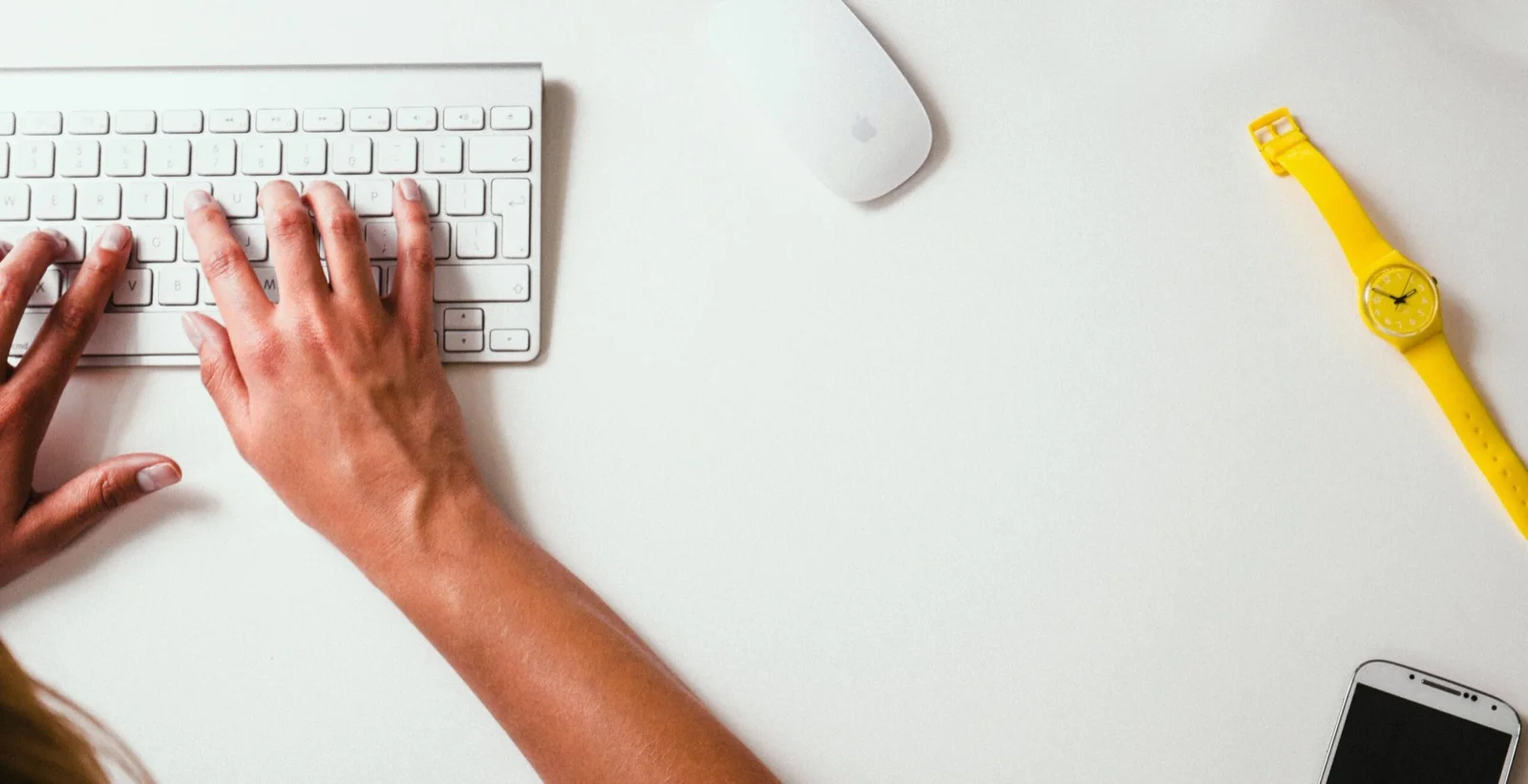 Hands on a computer keyboard, on a white desk