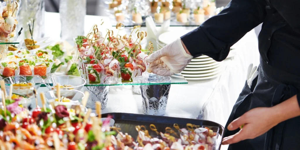 Gloved server arranging bites on a buffet