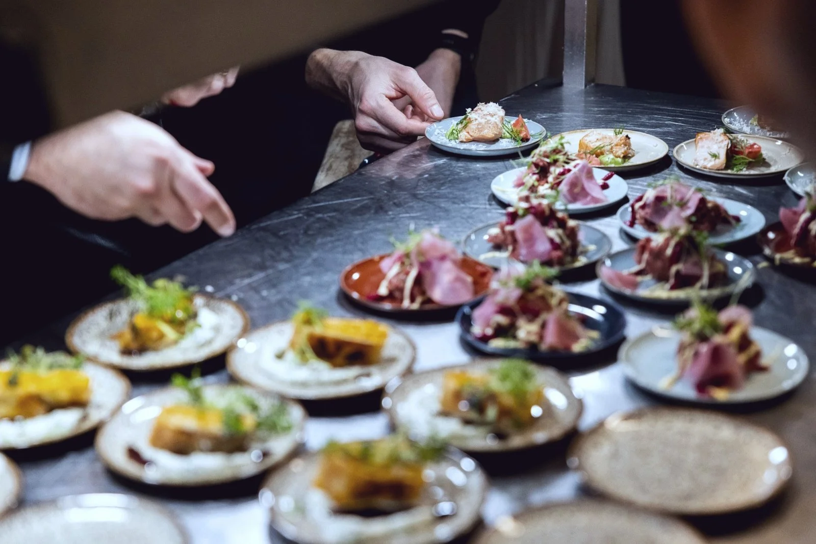 Kitchen team plating dishes in volume at the pass